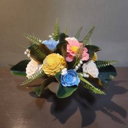 Small bouquet of pastel flowers with dark green leaves in a low container