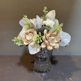Artificial floral arrangement in a glass vase with silver and cream flowers