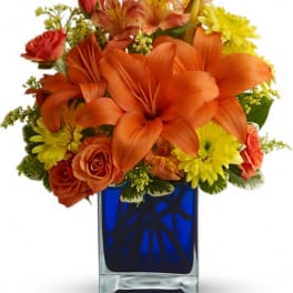 Orange lilies and roses in a blue glass vase
