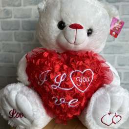 White teddy bear holding a red heart with embroidered love text