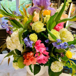 Colorful mixed flower arrangement in a white vase with roses and iris