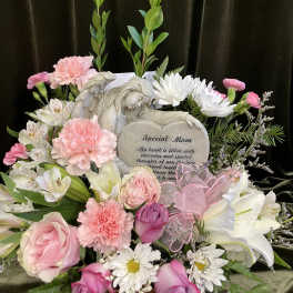 Pink and white floral arrangement with a memorial plaque and angel figurine