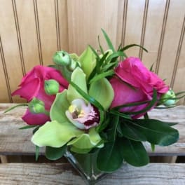 Pink roses and green orchids in a clear glass vase