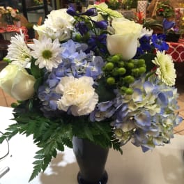 Blue and white mixed flower arrangement in a black vase