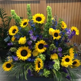 Large floral arrangement with sunflowers, yellow roses, and purple flowers