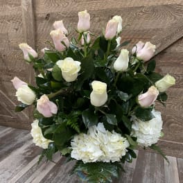 White and pale pink roses with white hydrangeas in a glass vase