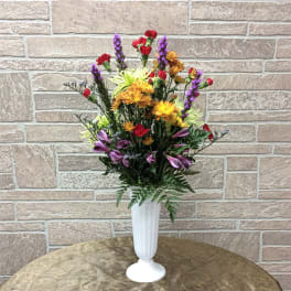 Mixed bouquet in a white pedestal vase with red, purple, and yellow flowers