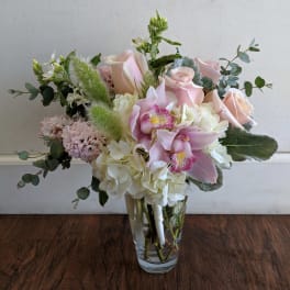 Pink roses and orchids arranged in a clear glass vase
