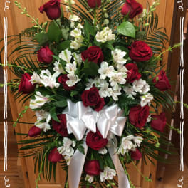 Standing spray of red roses and white flowers with a white ribbon bow