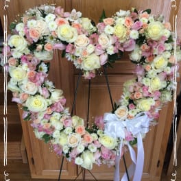 Heart-shaped floral wreath with pastel roses and a white ribbon bow