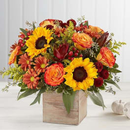 Autumn bouquet with sunflowers, orange roses, and mums in a wooden box