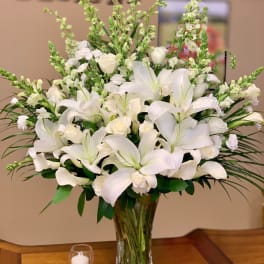 White lilies and roses arranged in a clear glass vase
