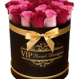 Round box of red and pink roses with a gold ribbon