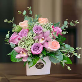 Pink and peach roses with orchids in a white box