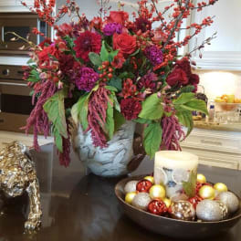 Large red and purple floral arrangement in a decorative vase on a table