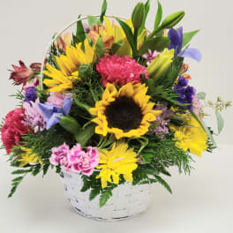 Colorful mixed flower basket with a sunflower and lilies in a white basket