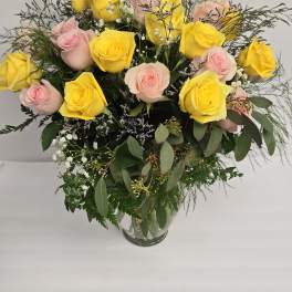 Bouquet of yellow and pale pink roses in a clear glass vase