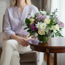Bouquet of white and lavender flowers in a green glass vase