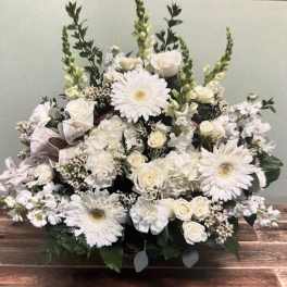White floral arrangement with daisies and roses in a low container
