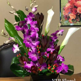 Purple orchids and white calla lilies in a black rectangular vase