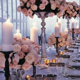 Pink rose centerpieces with white candles on a formal table setting