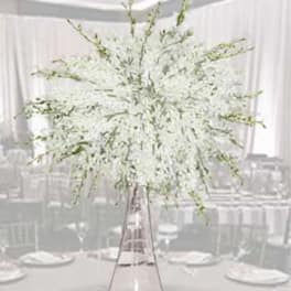 White floral centerpiece in a tall clear vase on a table