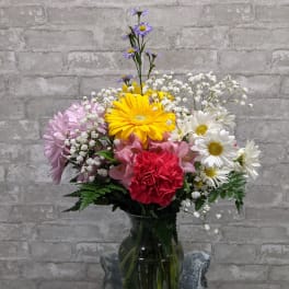 Mixed bouquet of daisies, carnations, and baby's breath in a glass vase