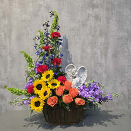 Mixed bouquet in a dark basket with sunflowers, roses, and purple blooms