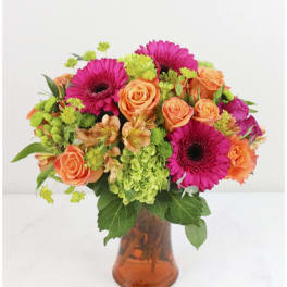 Bouquet of pink gerbera daisies and orange roses in an amber glass vase