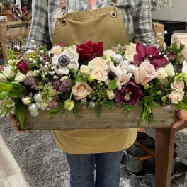 Low wooden box centerpiece with blush and burgundy flowers, white blooms, and silver ornament accents.