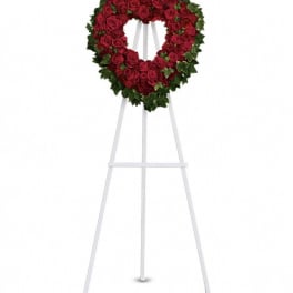 Heart-shaped wreath of red roses on a white standing easel