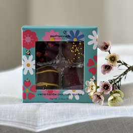 Box of chocolate truffles beside a small sprig of pink and white flowers
