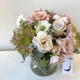 Pastel bouquet of roses, chrysanthemums, and white blooms in a glass vase