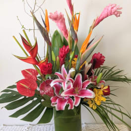 Tropical bouquet with pink lilies and red anthuriums in a glass vase
