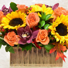 Sunflowers and peach roses in a rectangular vase with purple orchids