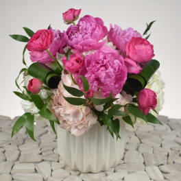 Pink peonies and roses arranged in a white vase
