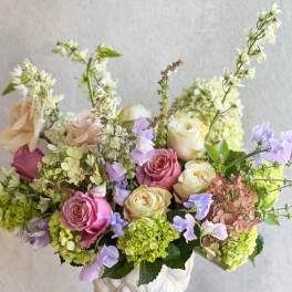 Mixed pink and cream roses in a white vase with lavender flowers