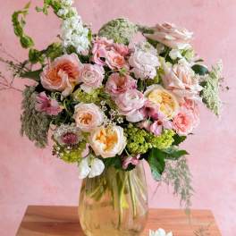 Pastel bouquet of roses, ranunculus, and mixed blooms in a glass vase