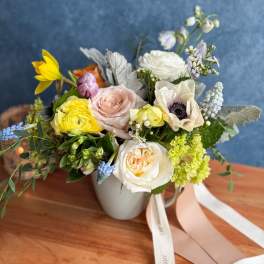 Mixed bouquet in a white mug-style vase with pastel roses and anemones