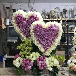 Two large heart-shaped rose arrangements in purple and white