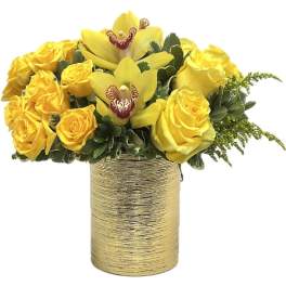 Low arrangement of yellow roses and orchids in a textured gold cylinder vase