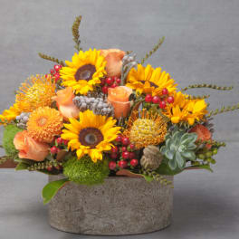 Sunflower and peach rose arrangement in a stone vase