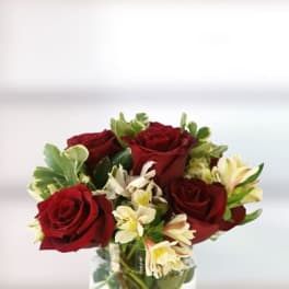 Red roses and pale lilies in a clear glass vase