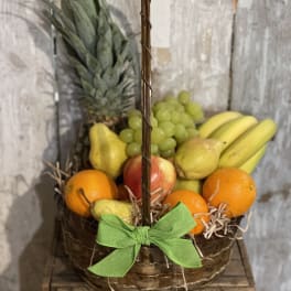 Basket of assorted fruit with a pineapple and green ribbon