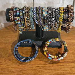 Display stand holding multiple beaded bracelets on a wooden surface