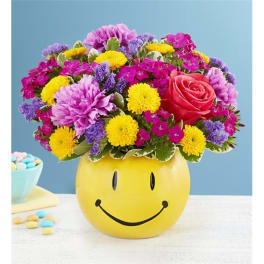 Mixed bouquet in a yellow smiley-face vase with a pink rose