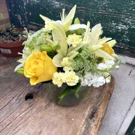 Yellow roses and white lilies arranged in a glass vase