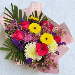 Mixed bouquet of roses, gerbera daisies, and chrysanthemums wrapped in pink paper
