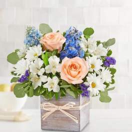 Peach roses and white daisies in a wooden box