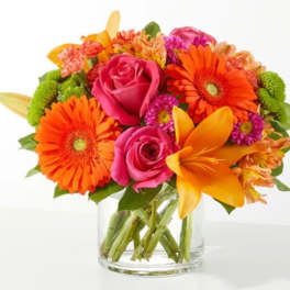 Bright mixed bouquet with pink roses, orange gerberas, and yellow lilies in a glass vase